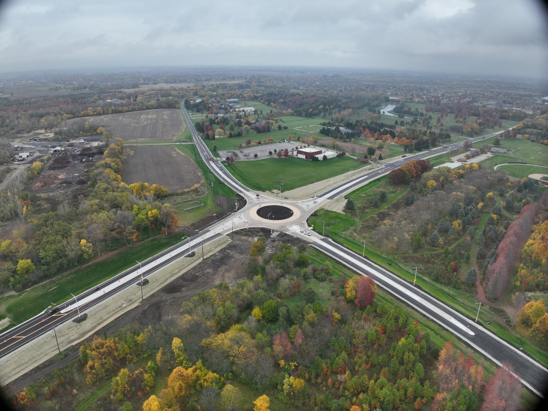 Aerial view of a roundabout with roads and green spaces, symbolizing community development.