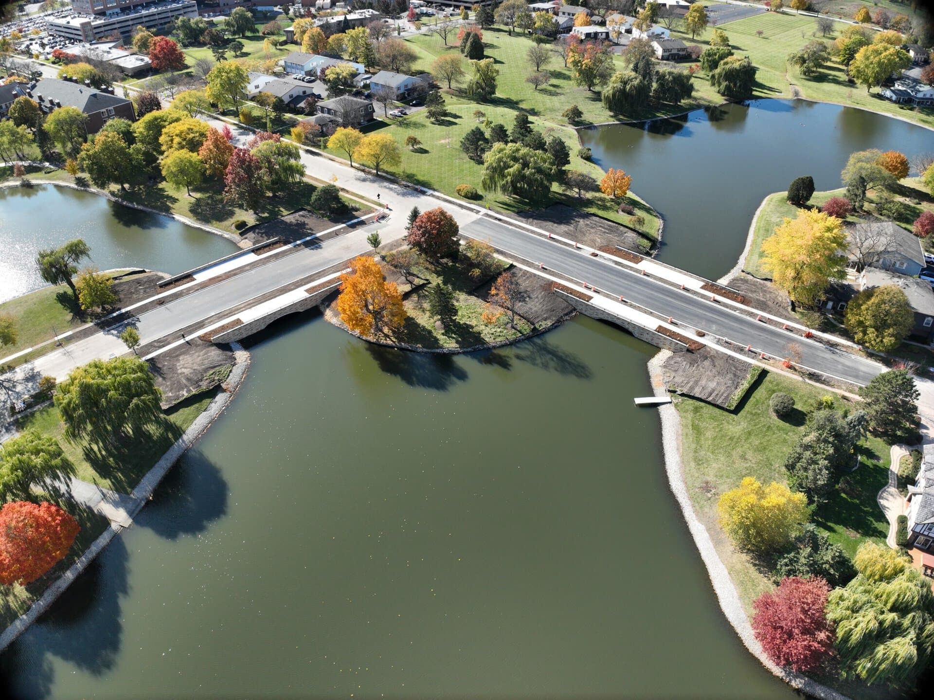 Bridge over scenic park with trees and water in autumn colors.