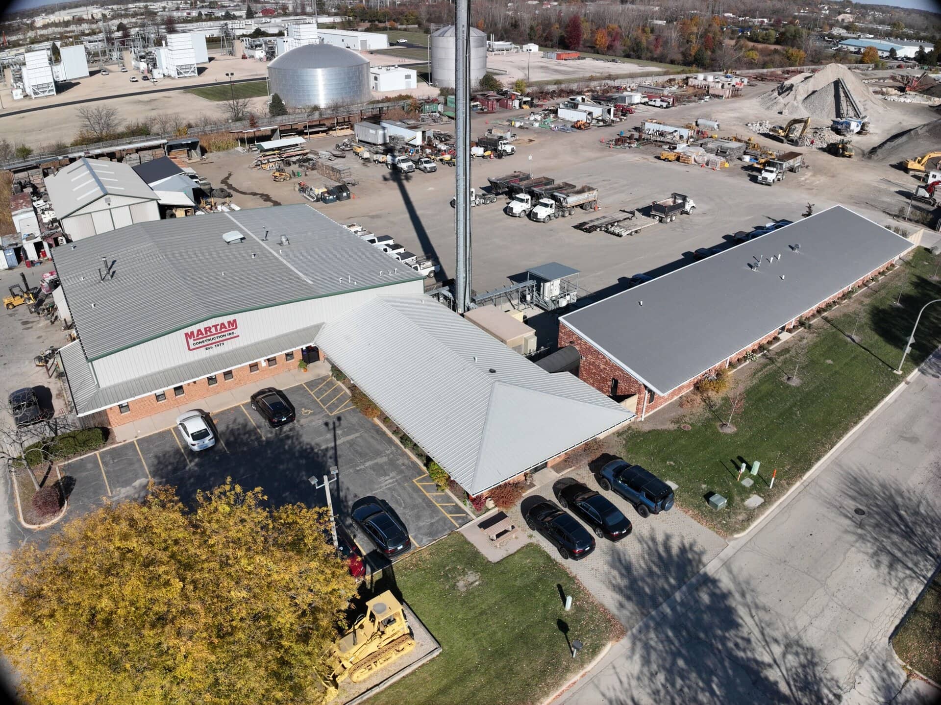Construction company building with parking lot and industrial background.