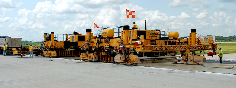 Slipform concrete paving equipment used for airport runway construction.